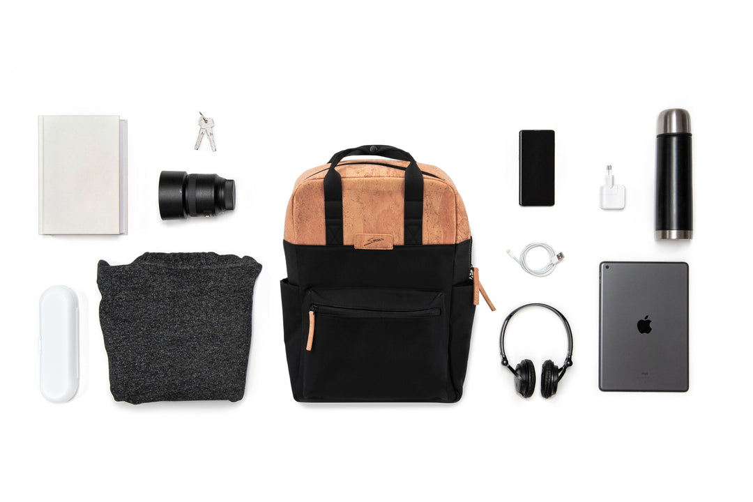 Collage mit schwarzem Rucksack mit hellen Korkteilen im Zentrum und ausgebreitetem Inhalt wie Kamera Equipment, Laptop, Trinkflasche etc. drum herum