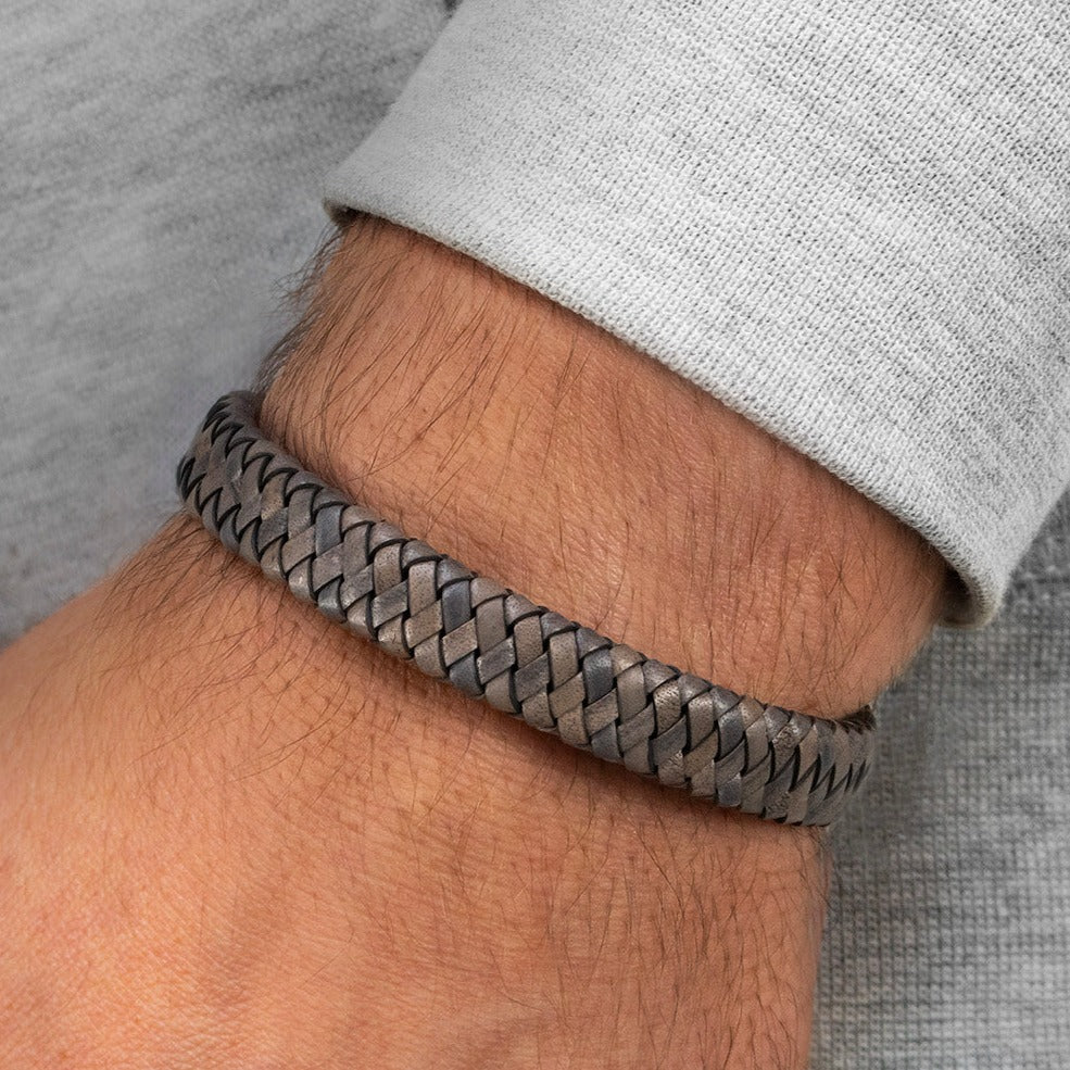 Breit geflochtenes Lederarmband in grauen Tönen an Herrenhandgelenk