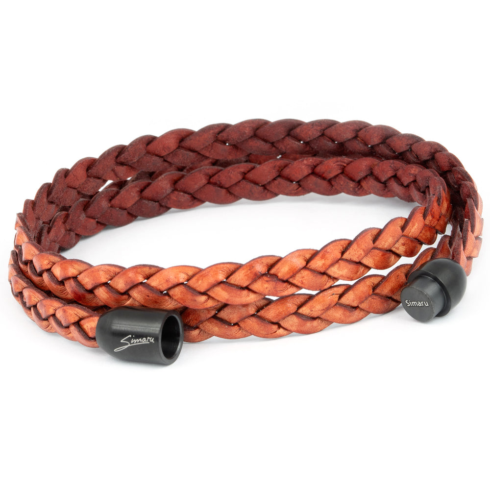 Breit geflochtenes Lederarmband in Rostbraun liegend mit offenem, schwarzem Magnetverschluss