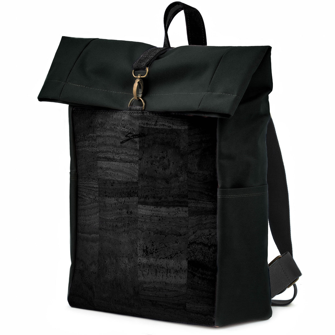 Leicht seitliche Ansicht geschlossener Rolltop Rucksack mit schwarzer Kork Front und schwarzem Stoff mit Karabinerverschluss, breiten Stoffträgern und Tragegriff aus Kork
