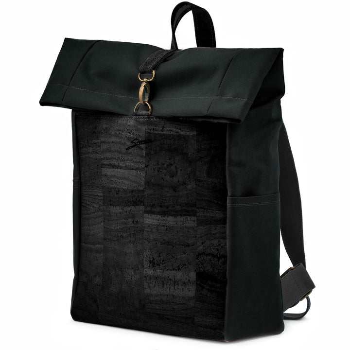 Leicht seitliche Ansicht geschlossener Rolltop Rucksack mit schwarzer Kork Front und schwarzem Stoff mit Karabinerverschluss, breiten Stoffträgern und Tragegriff aus Kork