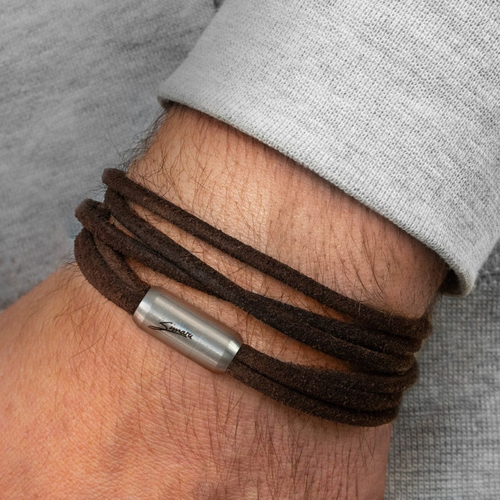Dunkelbraunes Lederarmband mit silbernem Magnetverschluss um Herrenhandgelenk gewickelt