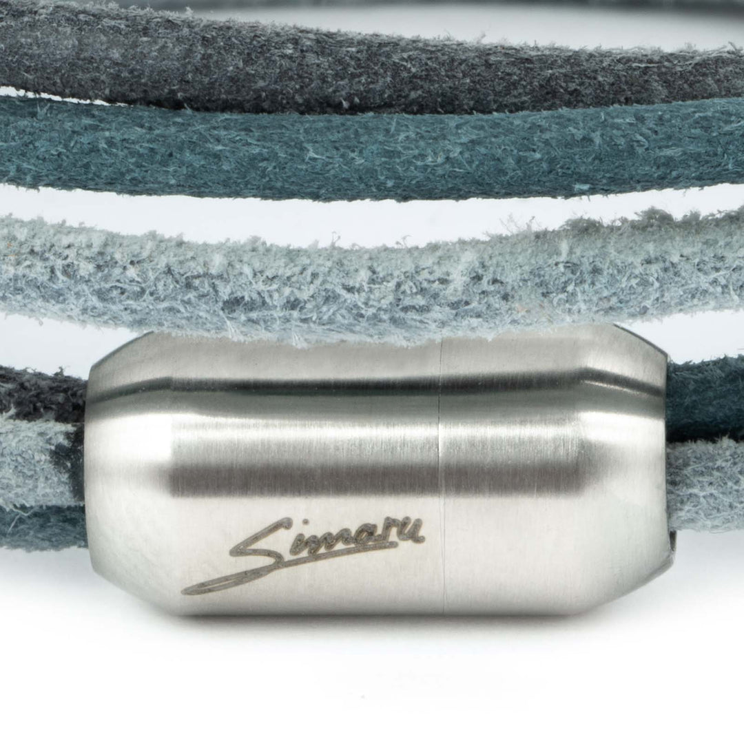 Großaufnahme silberner Magnetverschluss mit Simaru Schriftzug an blau-grauem Wickelarmband aus rauem Leder