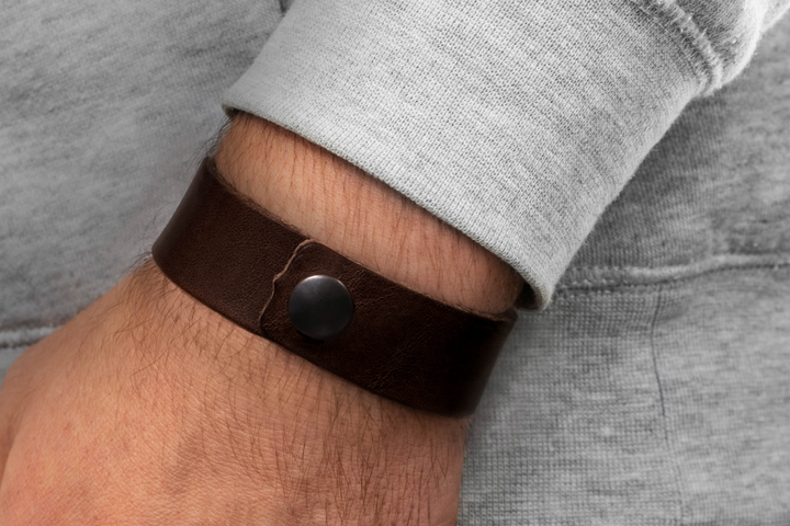 Breites, glattes Lederarmband in dunkelbraun mit Druckverschluss an Herrenhandgelenk #color_braun