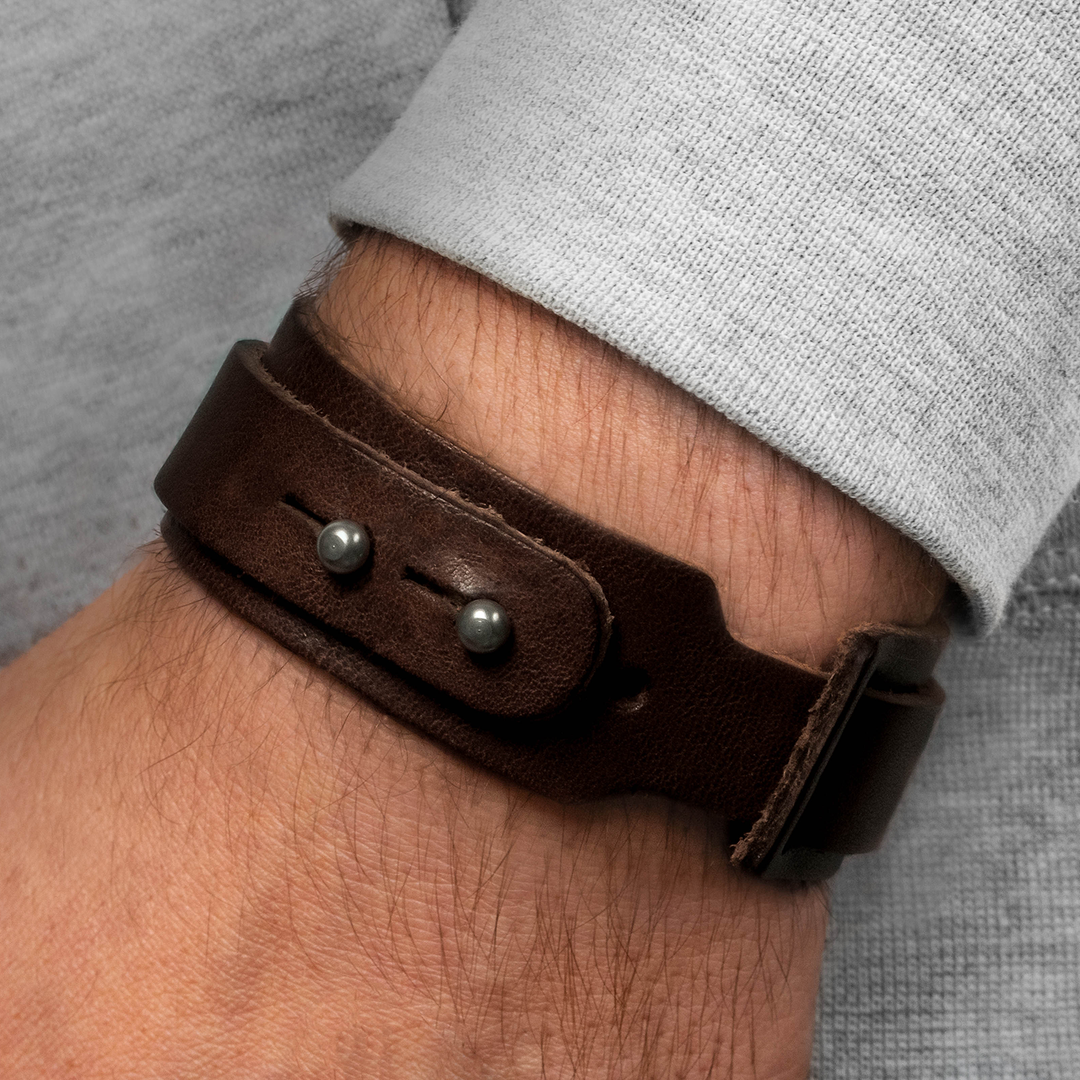 Breites, glattes Lederarmband in dunkelbraun mit Nietenverschluss an Herrenhandgelenk #color_braun