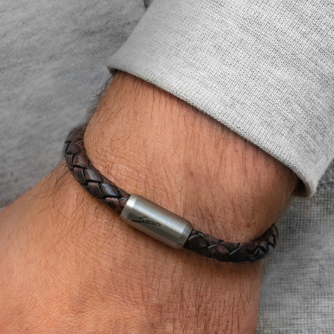 Braunes, geflochtenes Lederarmband mit silbernem Magnetverschluss um Herrenhandgelenk