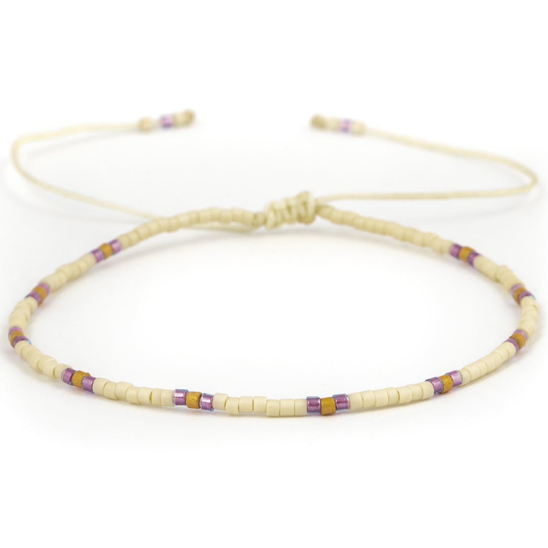 Armband mit einer Perlenreihe in weiß, lila und gold