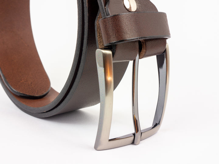 Nahaufnahme glänzende Gürtelschnalle an braunem Lederriemen #color_braun