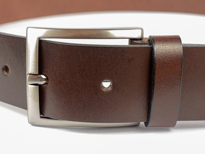 Nahaufnahme silberne Gürtelschnalle an braunem Lederriemen #color_braun