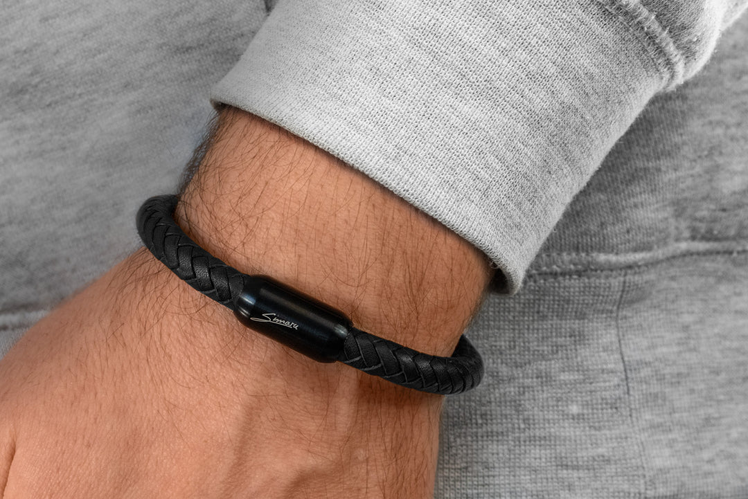 Breit geflochtenes, schwarzes Lederarmband mit schwarzem Magnetverschluss an Herrenhandgelenk #color_schwarz