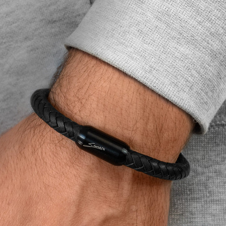 Schwarzes, geflochtenes Lederarmband mit schwarzem Magnetverschluss um Herrenhandgelenk