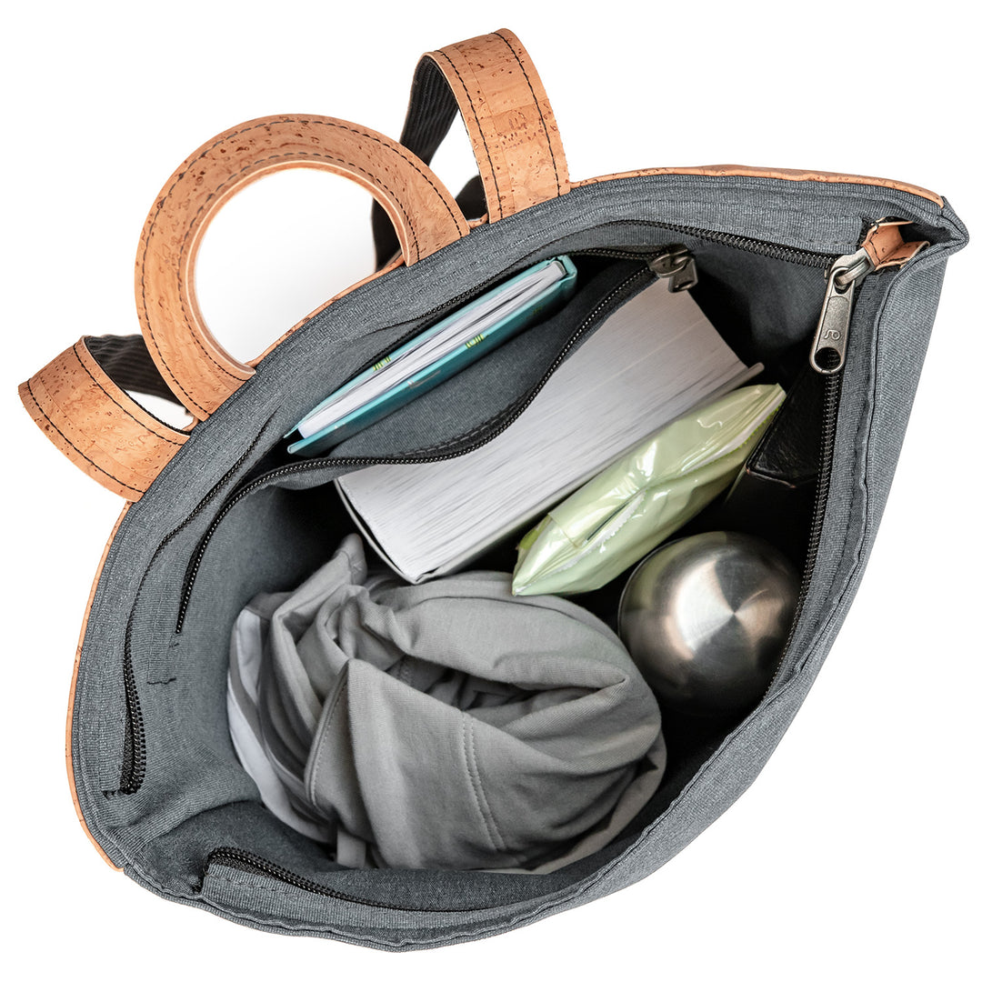 Draufsicht auf vollgepackten grauen Toploader Rucksack mit Büchern, Trinkflasche und Jacke