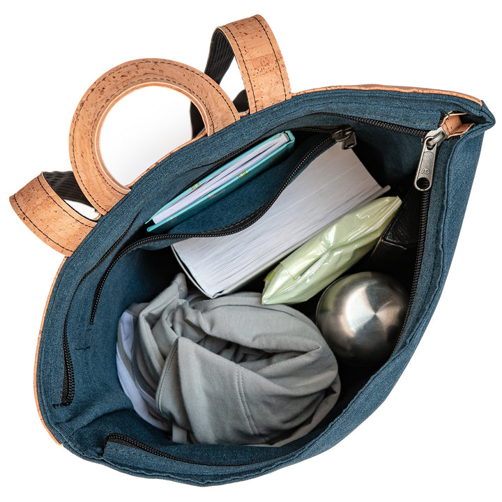 Draufsicht auf vollgepackten blauen Toploader Rucksack mit Büchern, Trinkflasche und Jacke