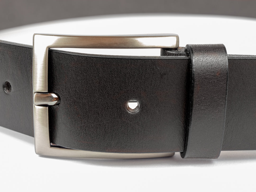 Nahaufnahme silberne Gürtelschnalle an dunklem Lederriemen #color_schwarz