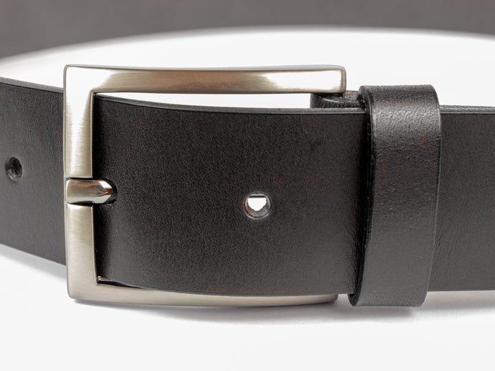 Nahaufnahme silberne Gürtelschnalle an dunklem Lederriemen #color_schwarz