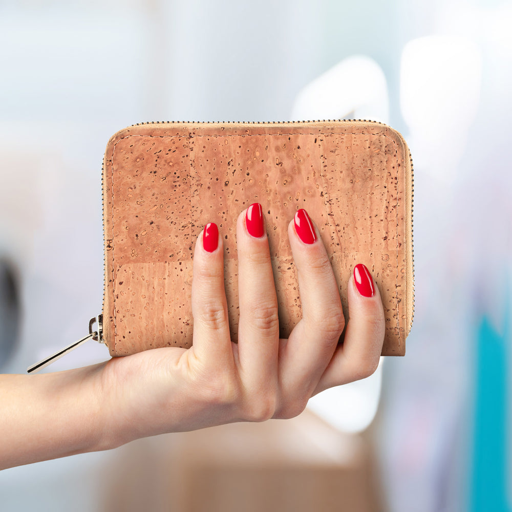 Frauenhand mit rot lackierten Fingernägeln hält kompakte Kork Geldbörse in der Farbe beige #color_beige