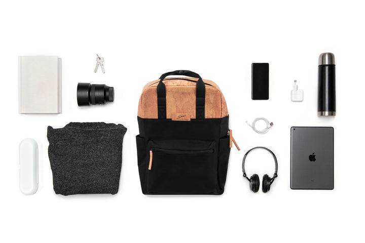 Collage mit schwarzem Rucksack mit hellen Korkteilen im Zentrum und ausgebreitetem Inhalt wie Kamera Equipment, Laptop, Trinkflasche etc. drum herum 