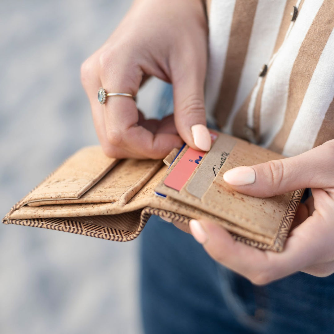 Frau zieht Karte aus aufgeklapptem Geldbeutel aus hellem Kork #color_vinicunca