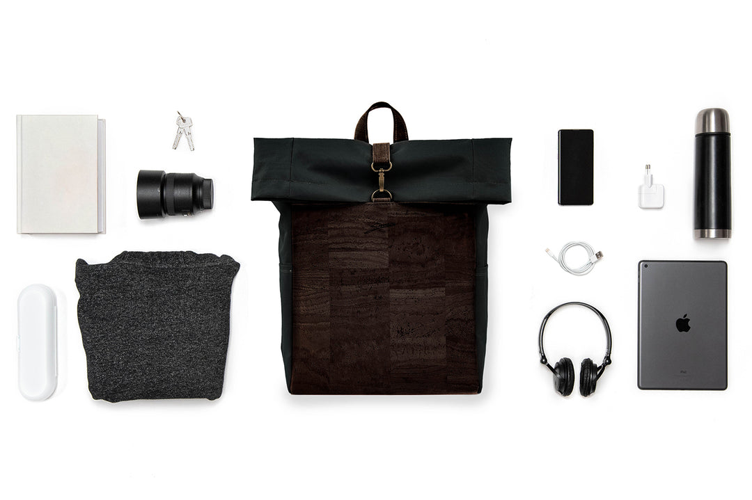 Collage mit schwarzem Toploader Rucksack mit dunkelbrauner Korkfront im Zentrum und ausgebreitetem Inhalt wie Kamera Equipment, Laptop, Trinkflasche etc. drum herum 