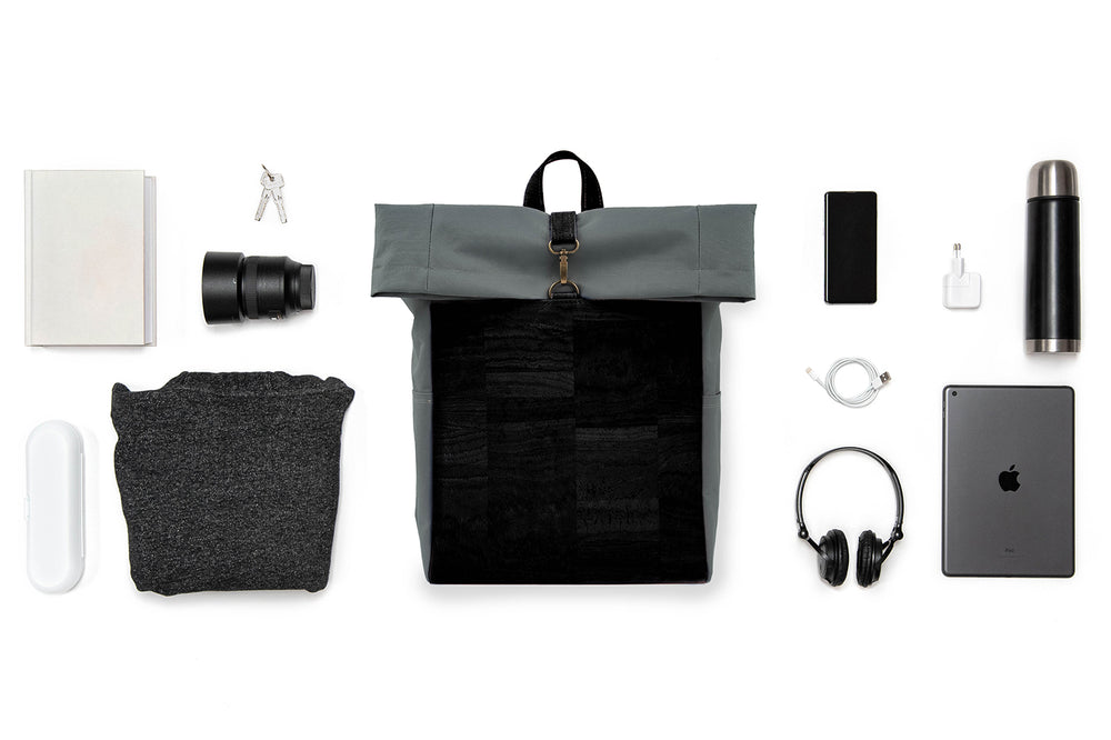 Collage mit grauem Toploader Rucksack mit schwarzer Korkfront im Zentrum und ausgebreitetem Inhalt wie Kamera Equipment, Laptop, Trinkflasche etc. drum herum 