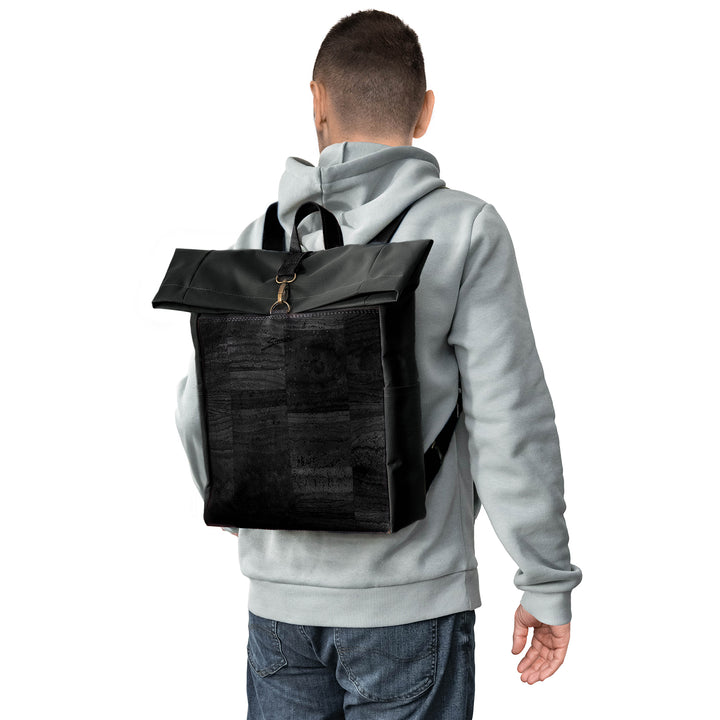 Rückansicht junger Mann mit hellem Pullover und Rucksack aus schwarzem Stoff mit schwarzer Korkfront auf dem Rücken