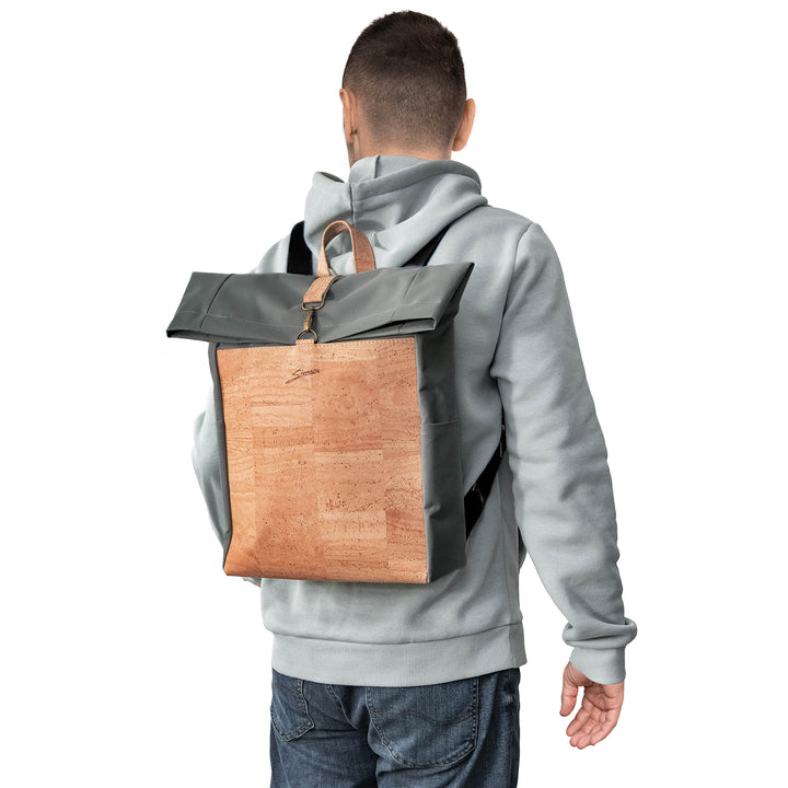 Rückansicht junger Mann mit hellem Pullover und Rucksack aus grauem Stoff mit heller Korkfront auf dem Rücken