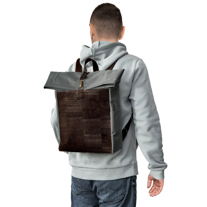 Rückansicht junger Mann mit hellem Pullover und Rucksack aus grauem Stoff mit dunkelbrauner Korkfront auf dem Rücken