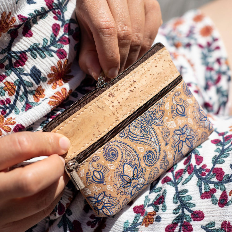Frau in hellem Sommerkleid öffnet Reißverschluss einer kleinen Münzgeldbörse aus hellem Kork mit Blumenmuster #color_bandana
