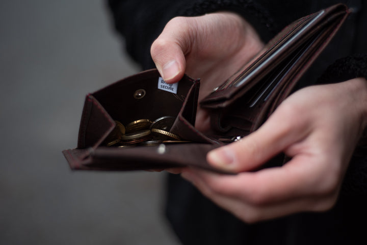 Person öffnet Münzfach eines braunen Kork Geldbeutels mit RFID-Schutz