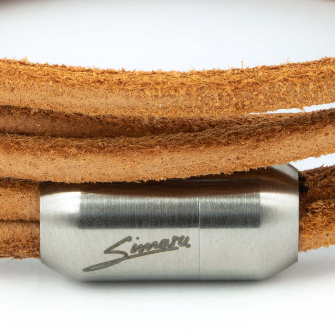 Großaufnahme silberner Magnetverschluss mit Simaru Schriftzug an hellbraunem Wickelarmband aus rauem Leder